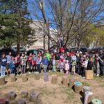 Families and Staff Stand around our outdoor classroom Stump seats