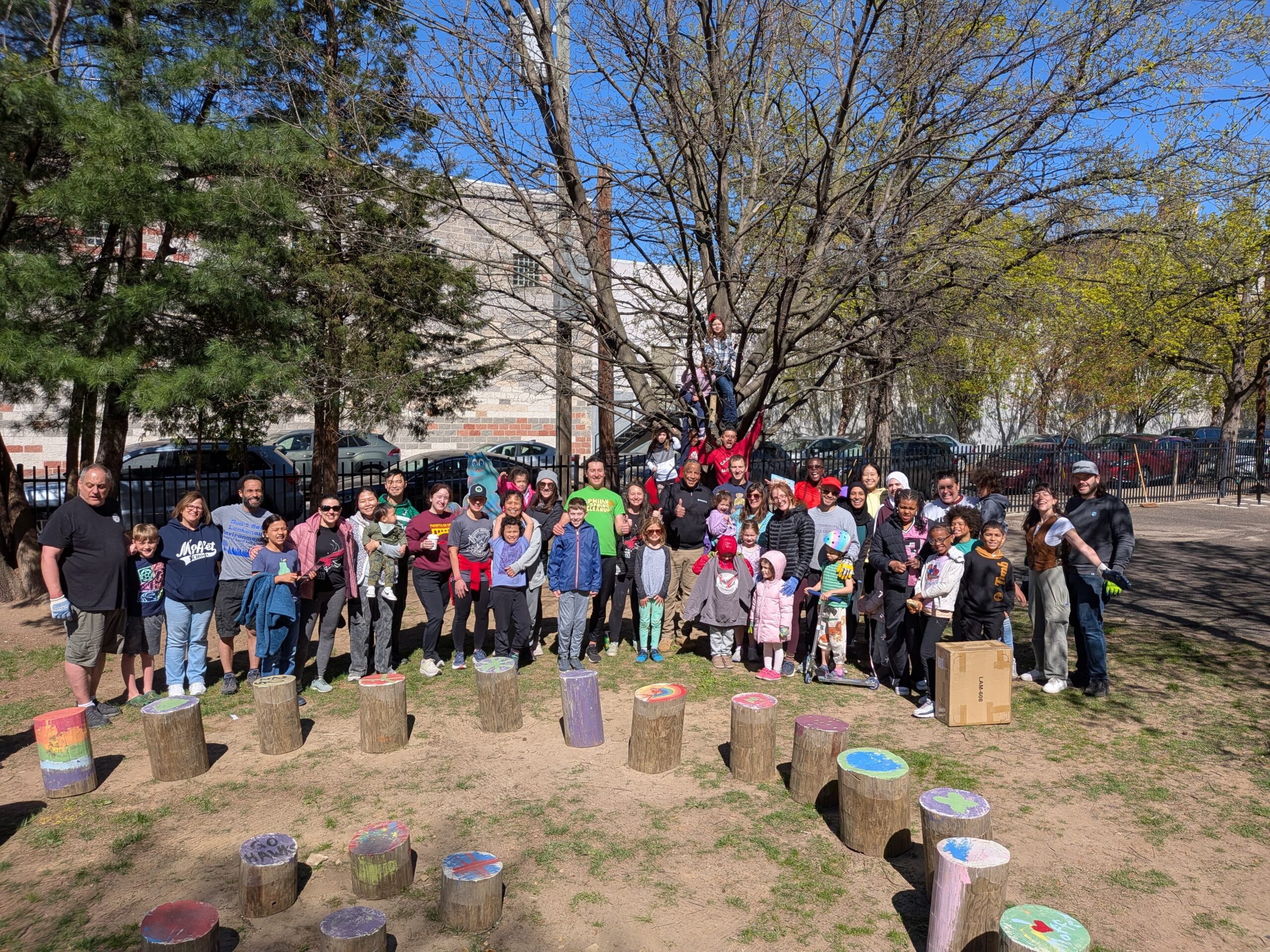 Families and Staff Stand around our outdoor classroom Stump seats